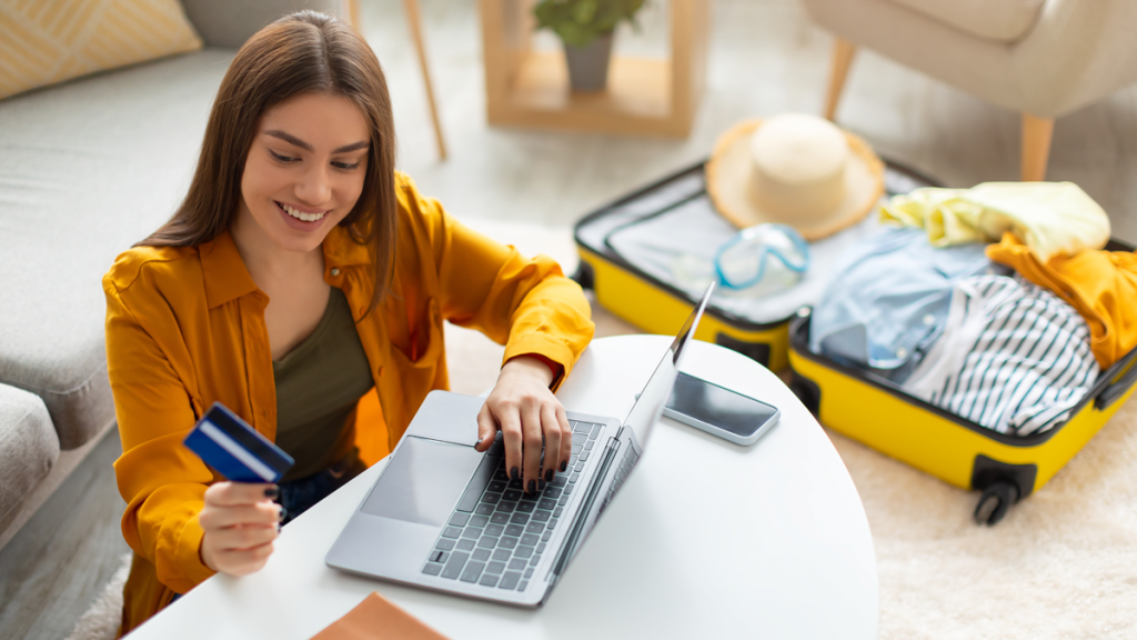 woman on her laptop, smiling and looking at a credit card
