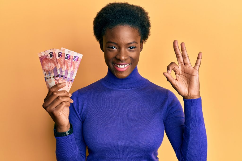 Young african american girl holding south african 50 rand banknotes doing ok sign with fingers, smiling friendly gesturing excellent symbol