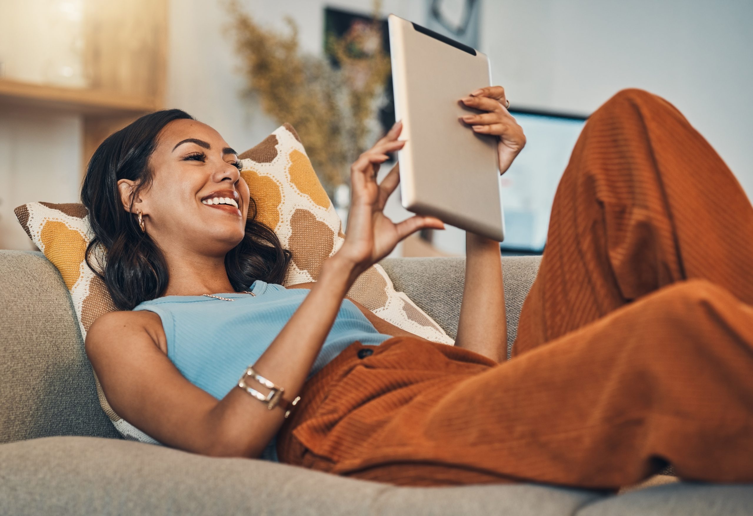 Woman relax on sofa with tablet, online streaming with internet and reading ebook or watching film at home. Happy female person with technology, subscription and mobile app with break in living room