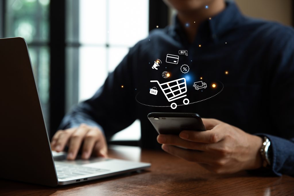 Young man using smartphone with shopping cart icon,  Online shopping and e-commerce concept.